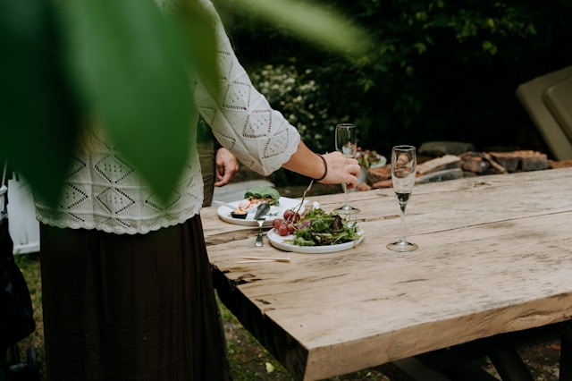 Frau-am-Holztisch-im-Garten-Teller-mit-Gemuese-und-Sektglas-1900